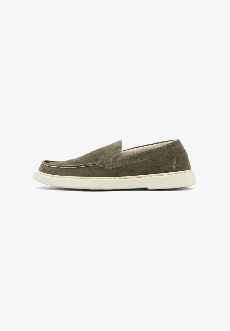 Παπούτσι slip-on από σουέντ σε ελιά πράσινο με στρογγυλεμένη μυτούλα, αντίθετη μπεζ σόλα από καουτσούκ και ραμμένα διακοσμητικά κατά μήκος του άνω μέρους.