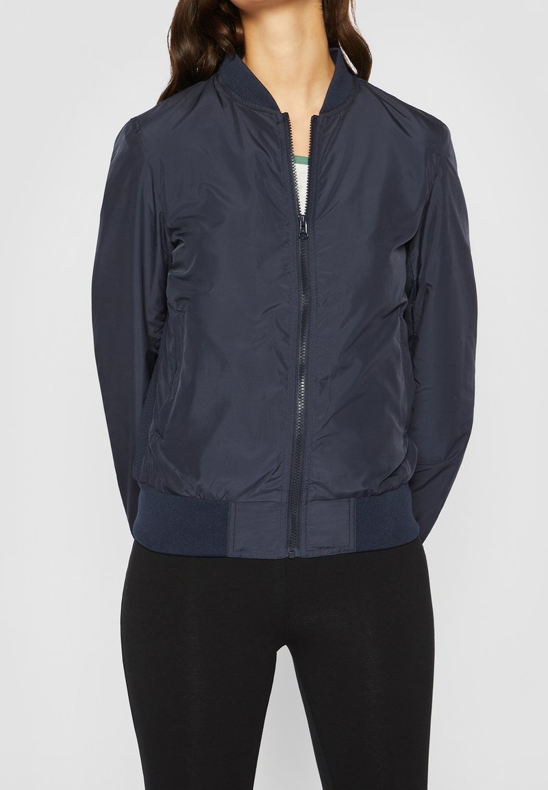Veste bomber bleu marine en tissu léger, avec une fermeture éclair à l'avant, un col et des poignets côtelés, une coupe ajustée et une taille élastique.