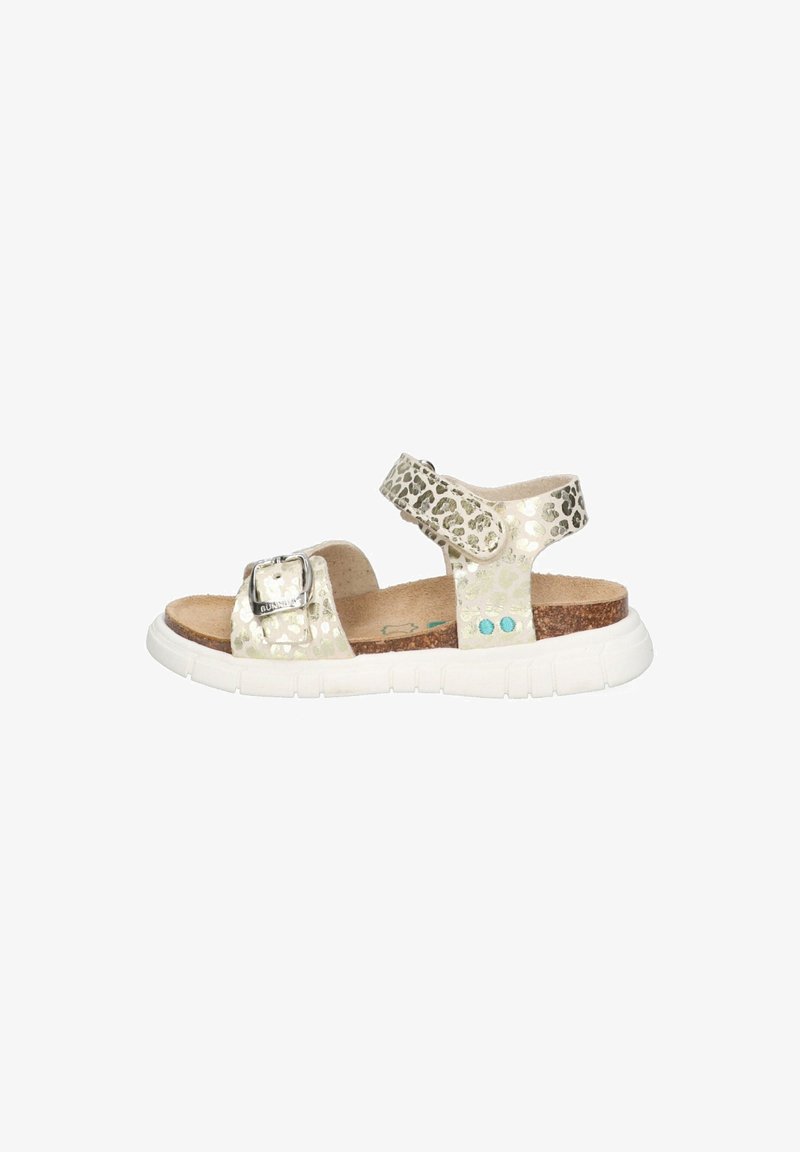 Light-colored sandal made of textured material with a leopard print, featuring a silver buckle, adjustable straps, and a white rubber sole.
