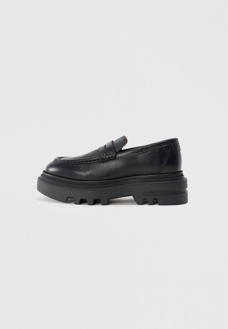 Zwarte leren loafers met een stevige zwarte zool en een gestructureerd banddetail. De gladde afwerking en de afgeronde vorm versterken het eigentijdse ontwerp.