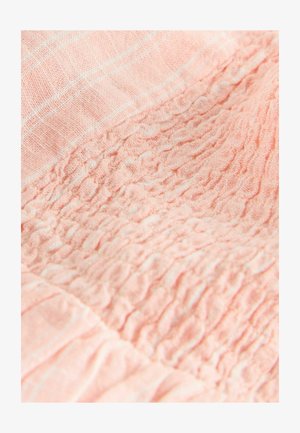 Weicher rosa Stoff mit gesammelter, geraffter Textur, die eine zerknitterte, elastische Oberfläche und ein sichtbares Webmuster in Nahaufnahme zeigt.