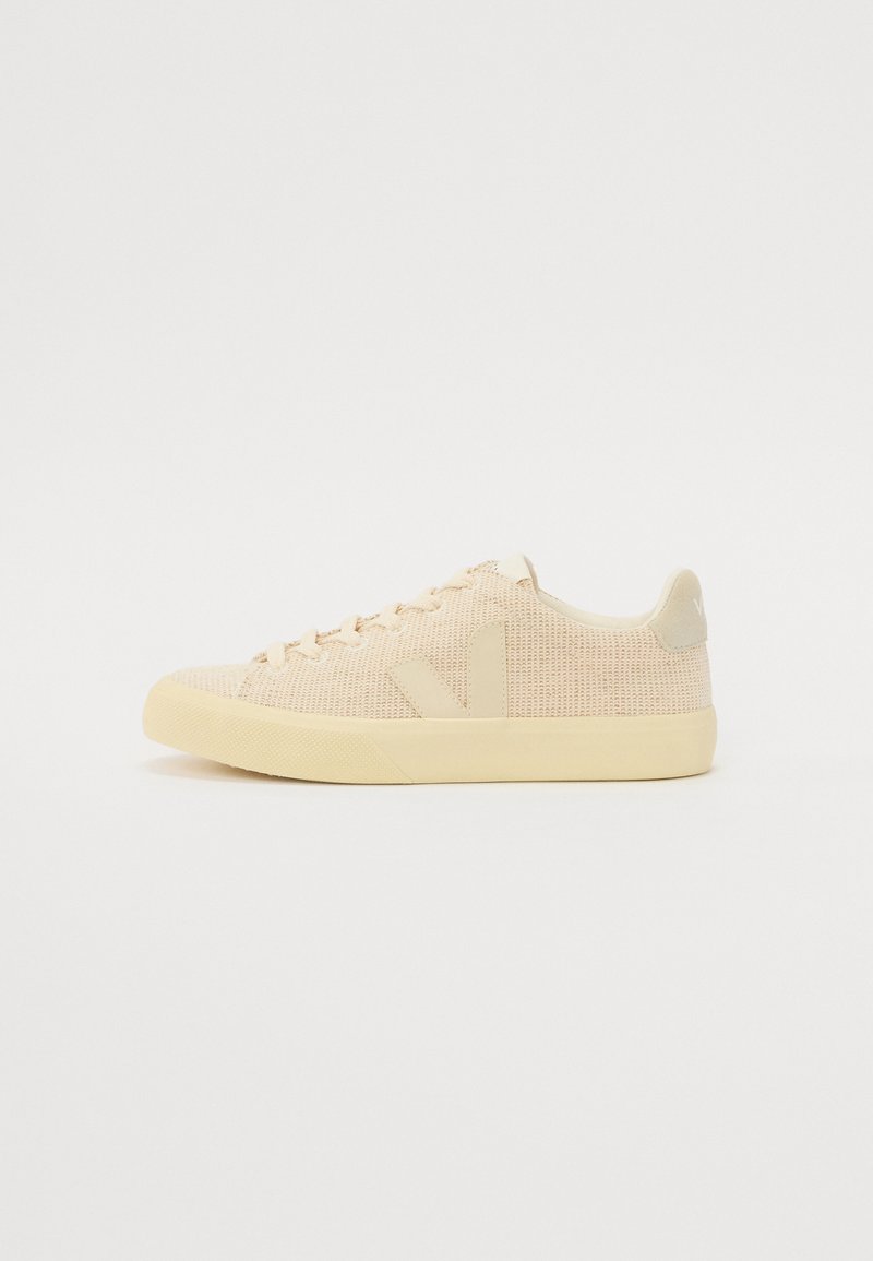 Sneakers in rete beige con una finitura testurizzata, caratterizzati da una punta arrotondata, lacci piatti e un logo discreto sul tallone. Suola in gomma.