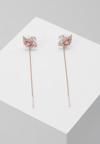 Øreringer i rosagull med hengende blomsterformer, innlagt med klare og rosa edelstener på en tynn kjede med rette stenger.