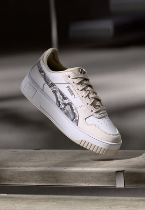 Cream-colored sneaker with a textured snake print accent on the side, featuring a smooth leather upper, lace-up design, and thick rubber sole.