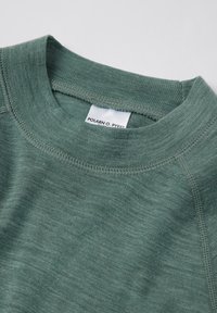 Vihreä pyöreä pääntie neulepusero, jossa on yksityiskohtaiset ompeleet pääntiellä ja pieni valkoinen brändilogo kauluksessa.