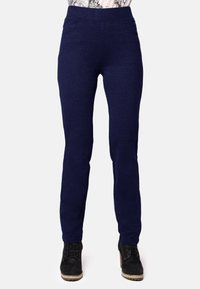 Pantalones elásticos de color azul marino con una cinturilla alta, corte ajustado, dos bolsillos laterales y una textura suave, combinados con botas negras con cordones.