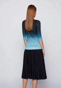 Pletený top v odstínech modré s gradientem, přecházející od tmavé k světlé, spárovaný s černou skládací sukní. Má tříčtvrteční rukávy.