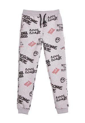 Pantalons de survêtement gris avec divers textes graphiques en noir et rouge ainsi que des impressions de crânes. Fabriqués en tissu doux, avec une taille élastique et des poignets.