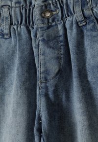 Svetlomodré džínsy majú elastický pás, kovové zapínanie na gombík a jednu bočnú kapsu s viditeľným šitím.