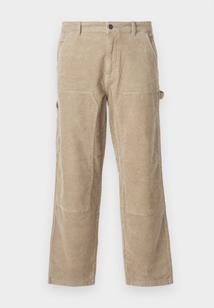 Beige Cordura-Hosen mit geradem Bein, ausgestattet mit Seitentaschen und verstärkten Knieflicken. Strukturiertes Gewebe mit vertikalen Rippungen.