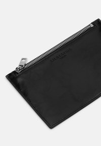 Pochette in pelle nera con finitura testurizzata, dotata di una cerniera argentata e del marchio impresso. Angoli arrotondati e dettagli hardware minimi.
