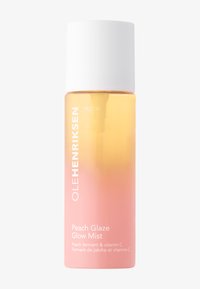 Bouteille de brume dégradée de pêche et de rose avec un capuchon blanc. L'étiquette indique "OLE HENRIKSEN TRUTH Peach Glaze Glow Mist" en lettres blanches en gras.