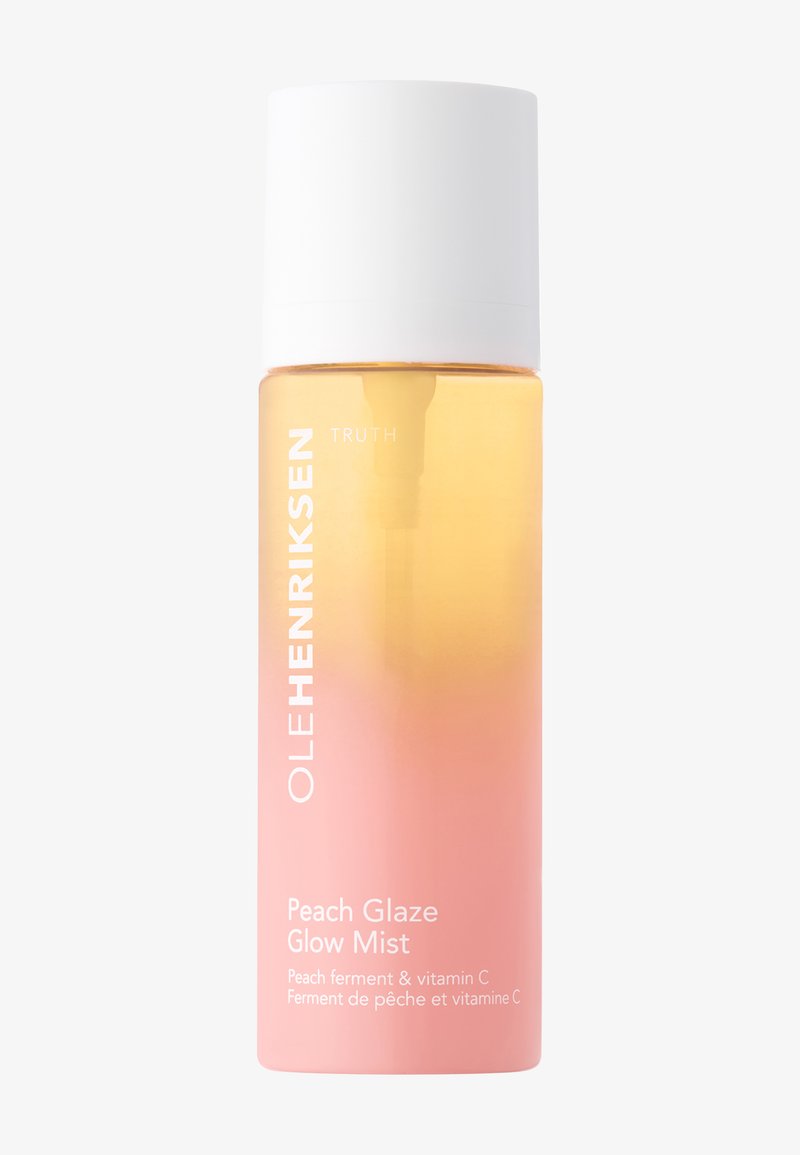 Bottiglia di una nebbia sfumata in pesca e rosa con tappo bianco. L'etichetta riporta "OLE HENRIKSEN TRUTH Peach Glaze Glow Mist" in grassetto bianco.