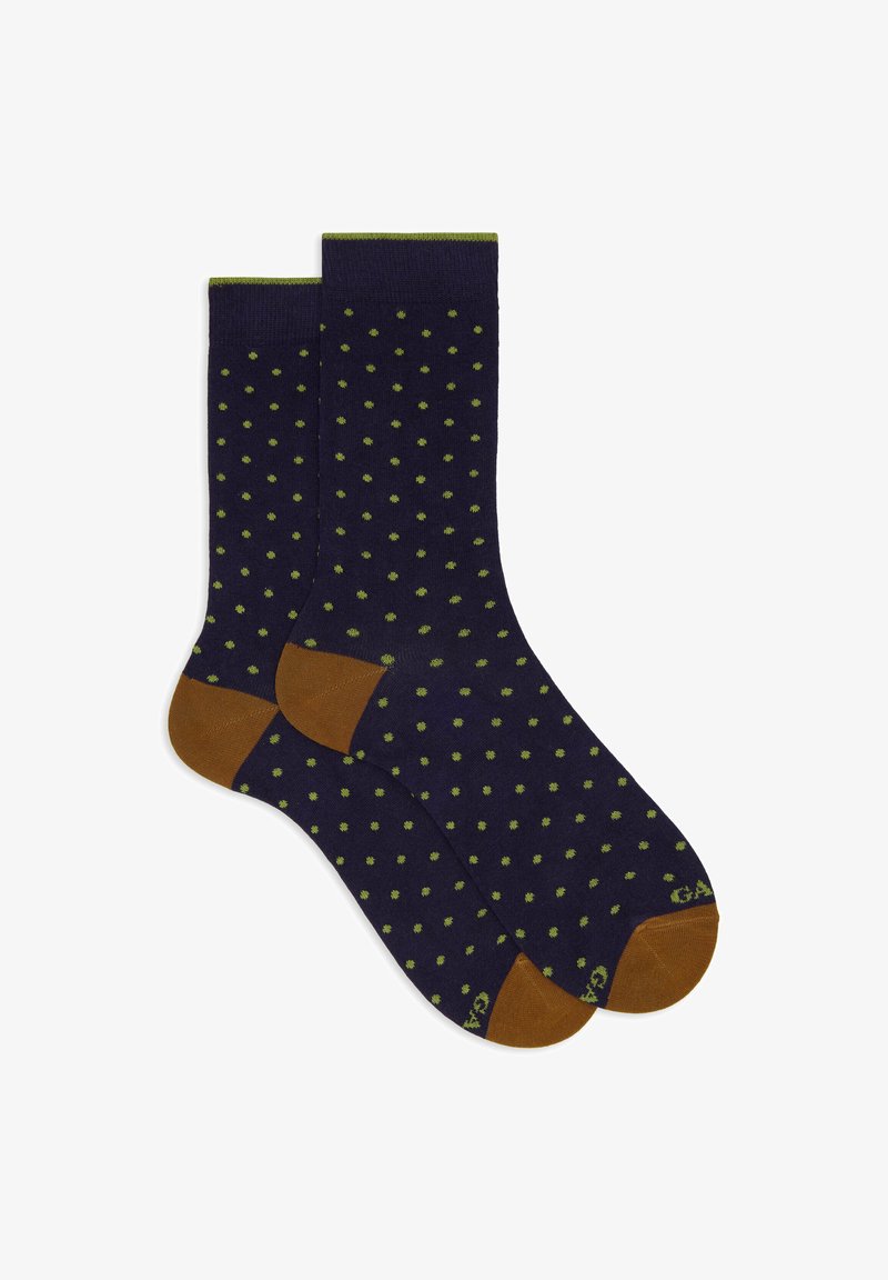 Marineblaue Socken mit kleinen grünen Punkten, braunen Fersen und Zehen sowie einem grünen Streifen an den oberen Kanten, flach ausgelegt.