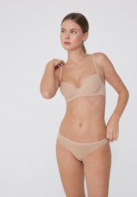Beiger BH und passender Slip, nahtloses Design, weicher Stoff, verstellbare Träger und glatte Textur mit minimaler Detailgestaltung.