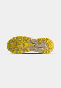 Semelle de chaussure de course Hoka avec un motif de semelle présentant des couleurs jaune et beige, conçue pour l'adhérence et la stabilité sur divers types de surfaces.