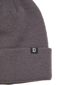 Sivá pletená čiapka s preloženým lemom, na boku s malou čiernou nálepkou s bielym logom. Textúrovaná, teplá tkanina.