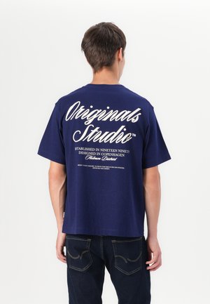 Navyblauwe katoenen T-shirt met witte grafische tekst op de achterkant, korte mouwen en een ontspannen pasvorm. De zoom is licht gebogen.
