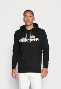 Zwarte hoodie met een voorste kangaroozak, witte koorden en een wit logo met een oranje accent. Geribde manchetten en onderrand.