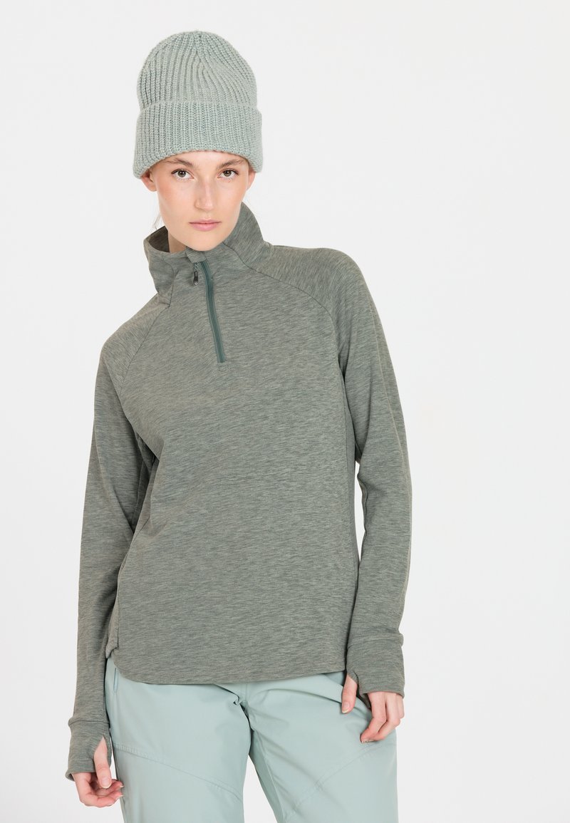 Letvægts grøn fleece pullover med lynlås krave, lange ærmer og tommelhuller, parret med en struktureret lys blå strikket hue.