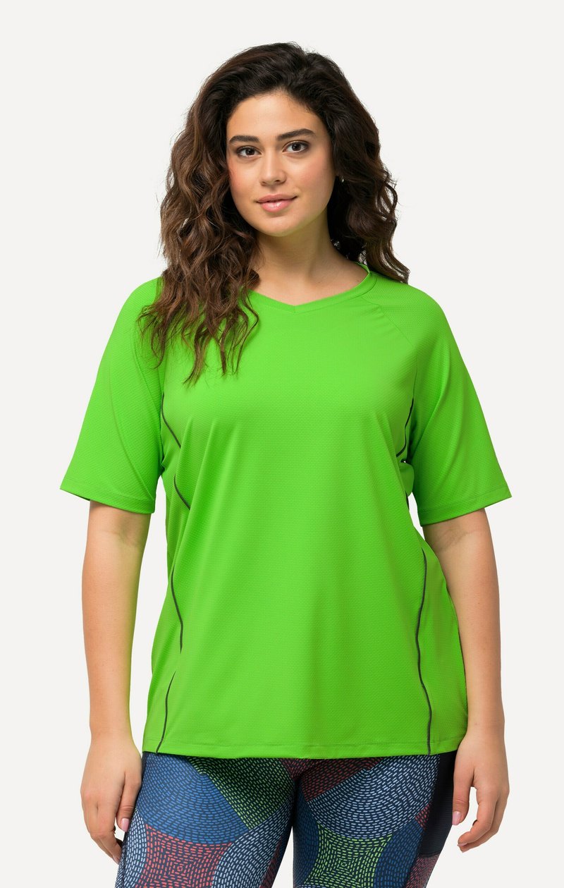 Maglietta sportiva verde a maniche corte con scollo a V e accenti neri ai lati, abbinata a leggings decorati con forme geometriche blu, rosse e bianche.