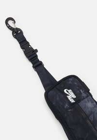 Donker marineblauwe verstelbare riem met een zwart en grijs getextureerde tas met een ritsluiting en een witte "JUMP MAN" logo. Haak voor bevestiging is inbegrepen.