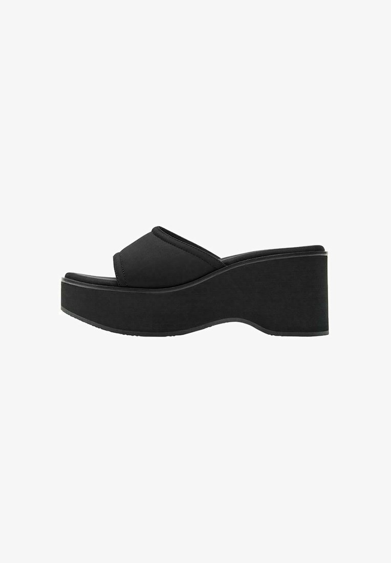 Sandale plateforme noire avec semelle épaisse et bout ouvert, avec une large bride sur le pied et une légère courbure du talon.