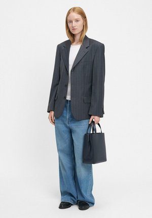 Przesadzone, szare marynarki w paski, biała koszula, szerokie niebieskie dżinsy, czarne buty i mała czarna torebka. Minimalistyczny design, usztywniony kształt.