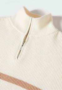 Pull en crème côtelé avec un col haut et une fermeture éclair mi-haute. Présente une bande horizontale marron sur la partie inférieure. Texture douce.