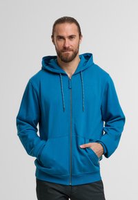 Niebieska rozpinana bluza z kapturem, z przednią kieszenią, regulowanym kapturem i kontrastowymi sznurkami. Wykonana z miękkiego, teksturowanego materiału.