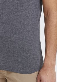 Grau, kurzärmliges T-Shirt aus weichem, strukturiertem Baumwollstoff mit tailliertem Design, präsentiert sich mit abgerundetem Saum und minimalen Nähten.