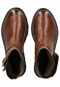 Botas de tobillo de cuero marrón con un acabado ligeramente brillante, puntera redondeada y cremalleras laterales. Suela texturizada con un sutil acento de costura.