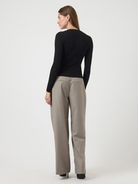 Μαύρη ριμπ μπλούζα με μακριά μανίκια συνδυασμένη με ανοιχτό γκρι παντελόνι ψηλής μέσης. Το σύνολο ολοκληρώνεται με μαύρες τακούνες.