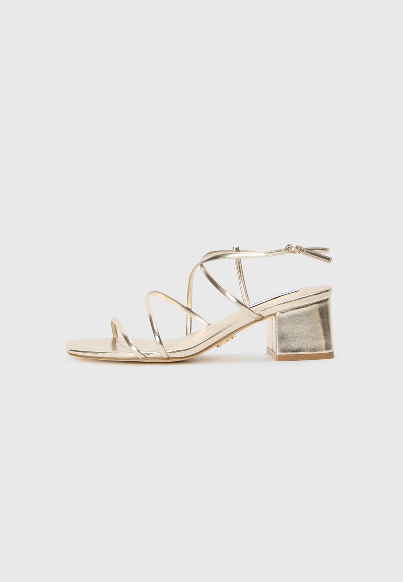 Gold metallic strappy sandal with a square block heel and open toe. Features thin straps and a back ankle strap for adjustment.