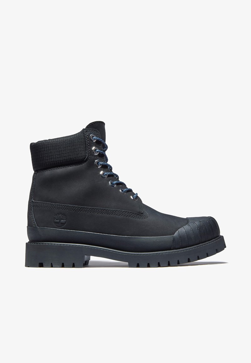 Schwarzer wasserdichter Knöchelstiefel mit texturiertem Kragen, Gummikappe und dickem Profilsohle. Verfügt über Metallschlaufen und runde Schnürsenkel.