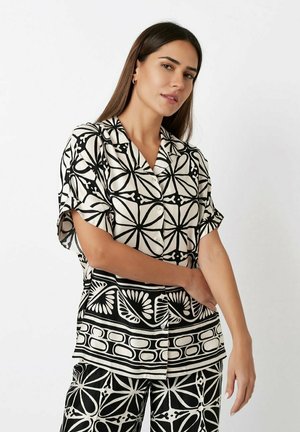 Black and white patterned shirt with short sleeves, a collar, and button front, paired with matching patterned pants. Smooth fabric texture.