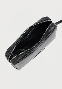 Μαύρο τσαντάκι με φερμουάρ κατασκευασμένο από υλικό με υφή. Το εσωτερικό είναι λείο. Διαθέτει ασημένιο φερμουάρ και γεωμετρικό σχέδιο στη μία πλευρά.