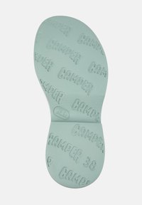 Mint green shoe insole featuring embossed "CAMPER" lettering and a textured surface for grip, designed for comfort and durability.