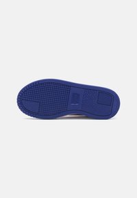 Sole di sneaker in gomma viola con motivi di presa testurizzati e dettagli del logo. Forma sagomata con bordi arrotondati per una vestibilità sicura.