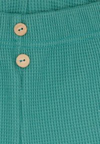 Tessuto testurizzato color turchese con piccoli motivi a nido d'ape, due bottoni in legno in vita e un aspetto morbido e lavorato a maglia.