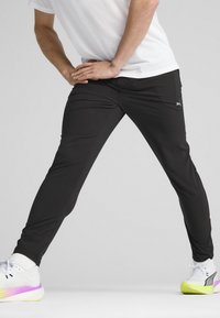 Zwarte sportbroek van rekbaar materiaal met een slim fit, voorzien van zijzakken en een klein logootje op het been.