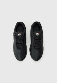 Black athletic shoes with a textured upper, round laces, and a circular logo detail on the tongue. Lightweight and streamlined design.