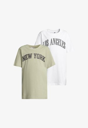 Világoszöld pamut póló, sötétszürke "NEW YORK" felirattal, fekete leggings-szel és fekete cipővel párosítva. Rövid ujjú, laza szabású.