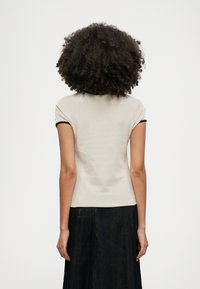 Κοντομάνικη ελαφριά μπλε μπλούζα με εφαρμοστή γραμμή, διακοσμημένη με σκούρο μπλε τελείωμα στο γιακά. Λείος υφάσματος, απλός χωρίς σχέδια.