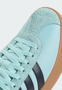 Jasnoniebieski sneaker z teksturowanym zamszowym noskiem, siateczkowym korpusem, czarnymi paskami i beżową gumową podeszwą. Posiada pasujące sznurowadła.