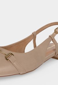 Μπεζ γυναικείο παπούτσι με χαμηλό τακούνι και λουράκι στο πίσω μέρος, με χρυσή μεταλλική αγκράφα, μυτερή μύτη, φόδρα από σουέτ και ρυθμιζόμενο λουρί.