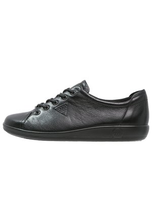 Baskets en cuir noir avec un bout rond, une silhouette basse et une finition texturée. Présente six œillets et un logo discret sur le côté.
