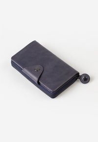 Portafoglio in pelle viola con chiusura a scatto e design a zip. Presenta una superficie texurizzata e un cursore della zip rotondo con un accento metallico.