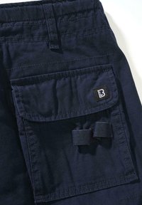 Marinblå cargo-byxor av slitstarkt tyg, med en stor framficka, sydda sömmar och en liten logotypmärke på fickan.