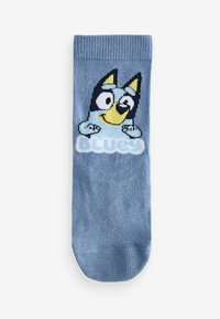 Blå børnesok lavet af blødt materiale; har et tegnefilmsfigur med en gul næse, sorte ører og ordet "BLUEY" i hvid tekst.